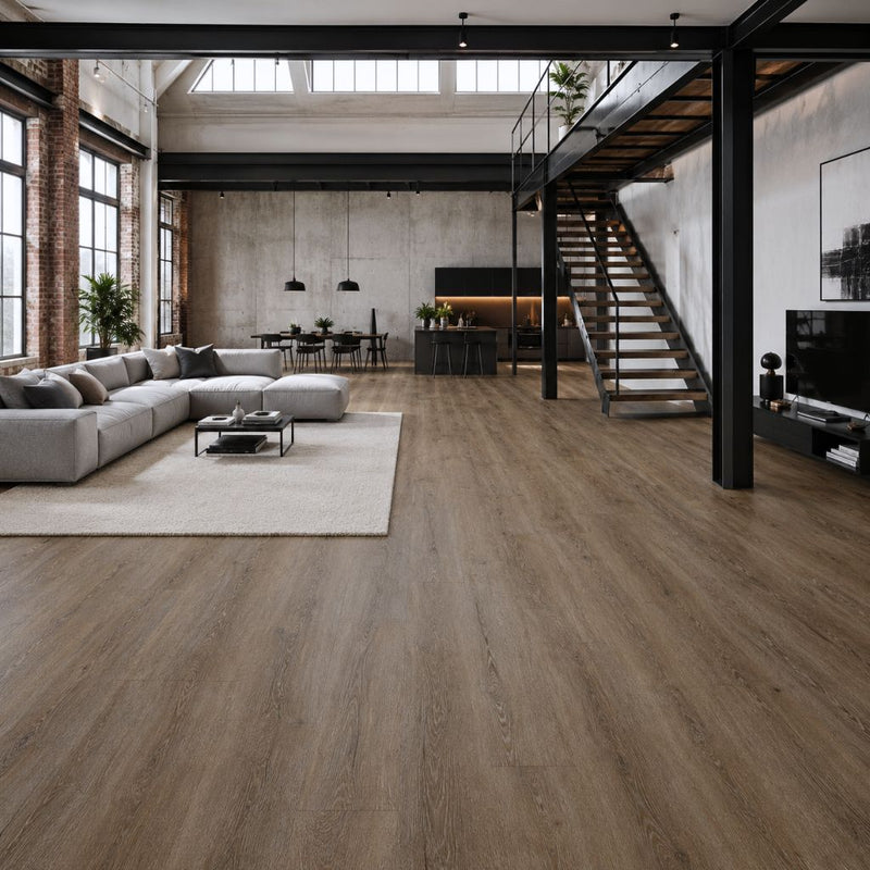 Moderner Loft-Wohnraum mit durchgehend verlegtem Vinylboden River Oak Brown, zeigt die großformatige Diele in einer geräumigen Industriallofts mit Stahlträgern, Betonwänden, Treppe und modernem Interieur- Floor4all